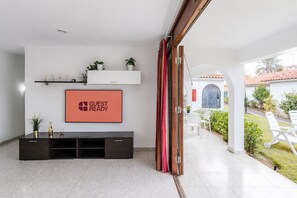 Ein modernes Wohnzimmer mit Flachbildfernseher, einer Unterhaltungsecke aus dunklem Holz und einem roten Vorhang.