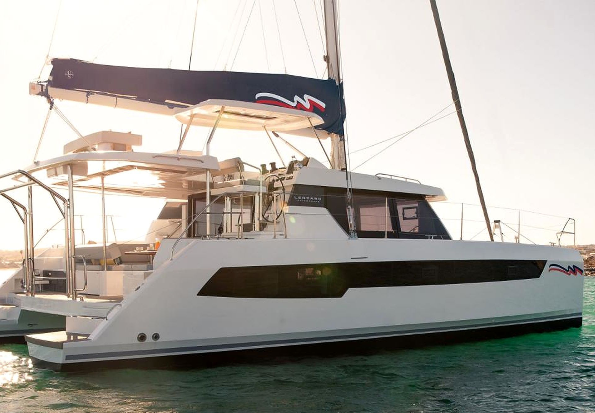 A large white yacht with a covered deck area and a logo on the side.