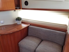 A compact RV interior with a wooden counter, a cushioned bench, and a potted plant. - Sun-Kissed Sailing Adventure in Islas Baleares, Mallorca (Andratx)