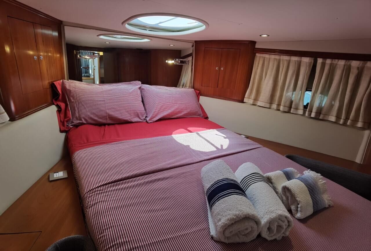 A bed with a red and white striped bedspread, two pillows, and rolled towels.
