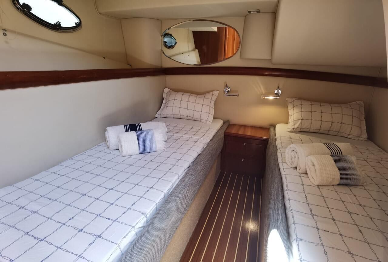 A compact cabin with two beds, a small table, and a mirror.