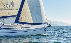 A sailboat with a website URL on its sail, sailing on calm waters.