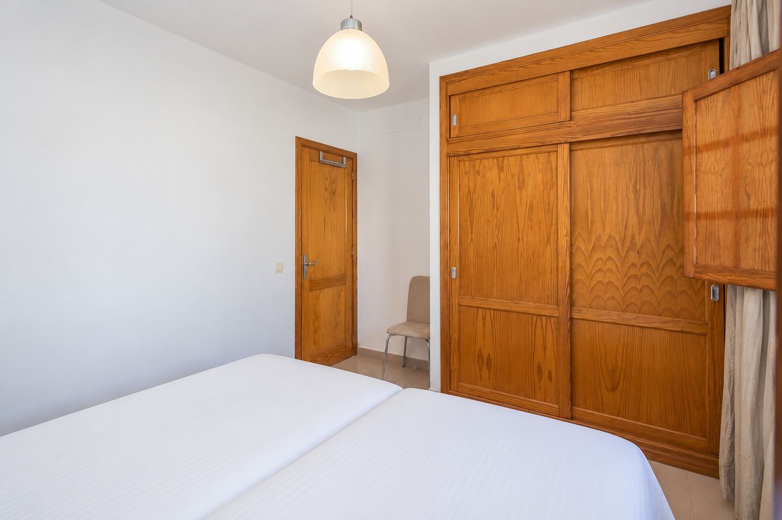 Une chambre à coucher avec un lit, une armoire en bois et une chaise.