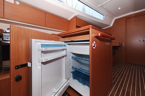 A compact kitchen with a built-in refrigerator, wooden cabinetry, and a window above the sink. - Sibenik Sun-soaked Sailing: A Luxurious Croatian Voyage (Pirovac)
