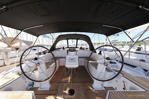 Cubierta de barco con timón, panel de control y toldo.