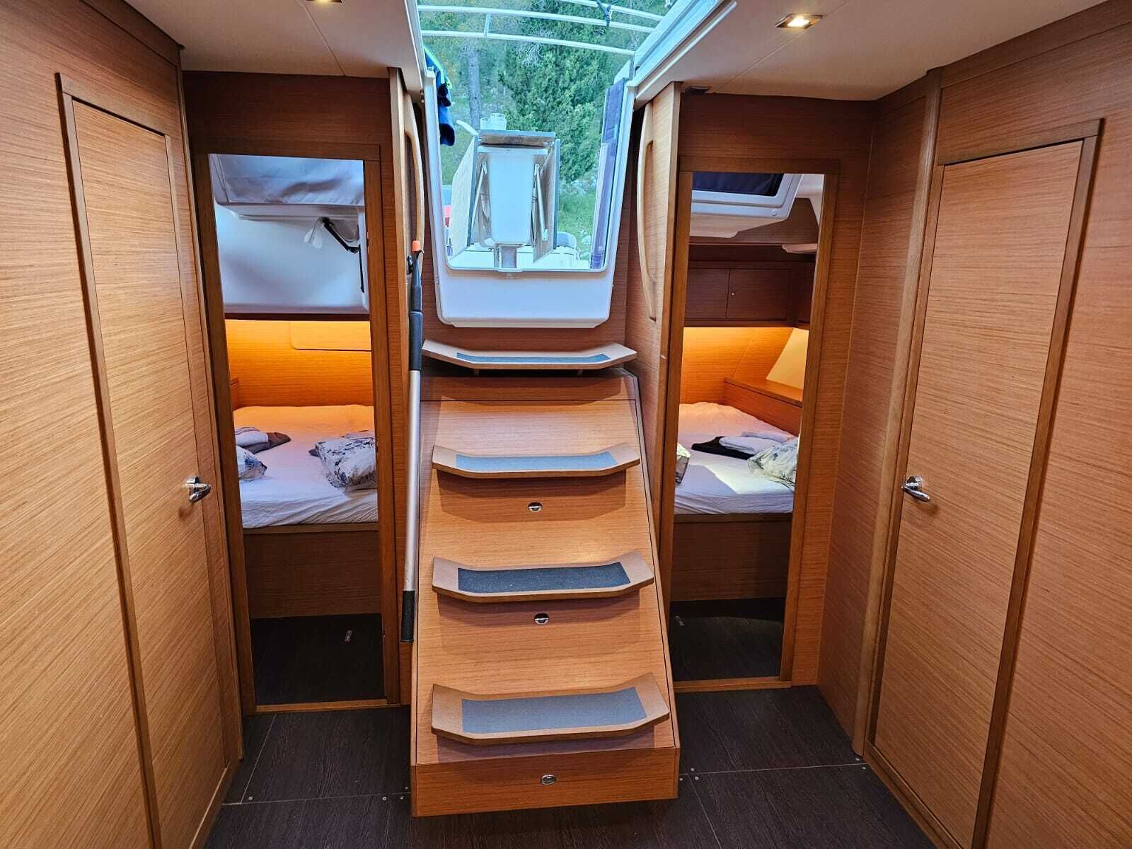 A compact, well-lit interior with a central staircase leading to upper bunk beds, wooden walls, and a skylight.