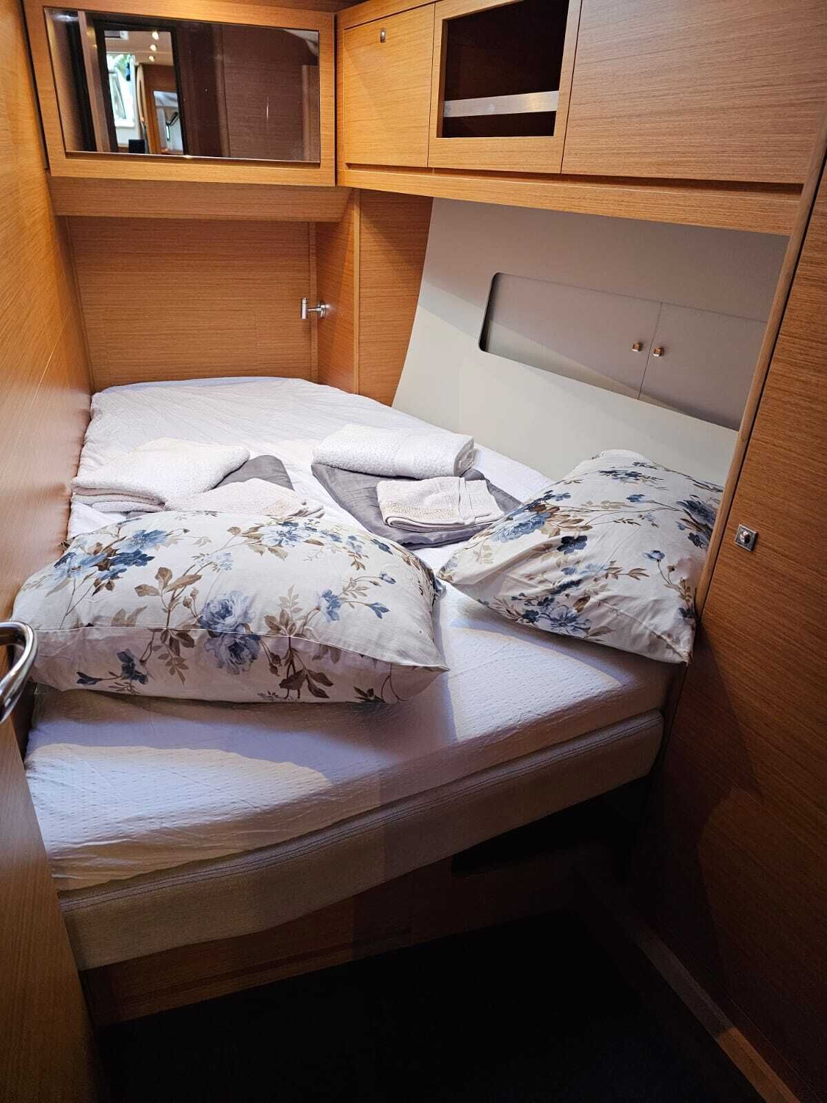 Ein kleines Bett mit floralem Bettzeug, ein Holzschrank und eine Kommode mit Spiegel.