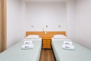 Ein Hotelzimmer mit zwei Einzelbetten, einem Holfnachtkästchen, einem Telefon und einem 'Guest Ready'-Schild auf jedem Bett.