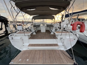 A sailboat with a covered deck, a steering wheel, and a life preserver.
