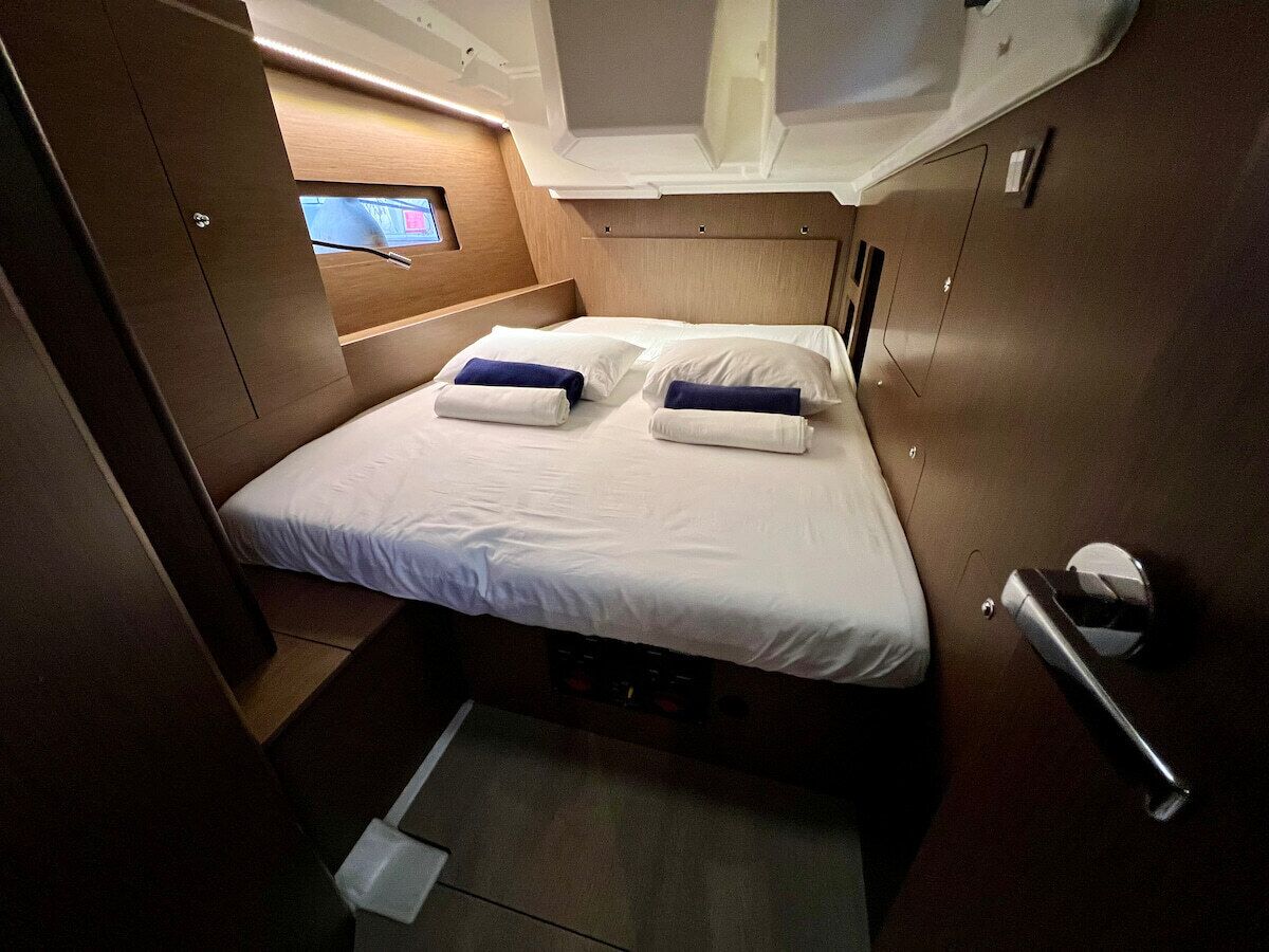Une cabine compacte et bien éclairée, équipée d’un lit simple, d’un petit coin salon et d’un écran de télévision.