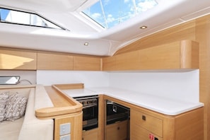 A compact kitchen with a skylight, wooden cabinets, a stove, and a dishwasher. - Sun-Kissed Sailing Adventure in Zadar, Croatia (Biograd na moru)