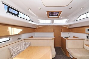 A compact, well-lit interior with a central seating area, a small kitchenette, and skylights. - Sun-Kissed Sailing Adventure in Zadar, Croatia (Biograd na moru)