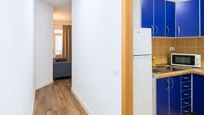 Una cucina compatta con mobili azzurri, un frigorifero bianco e un forno a microonde.