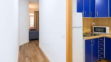 Una cocina compacta con armarios azules, un refrigerador blanco y un microondas.