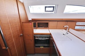 A compact kitchen with wooden cabinetry, a built-in oven, and a window above the sink. - Sibenik Sun-soaked Sailing: A Luxurious Croatian Voyage (Pirovac)