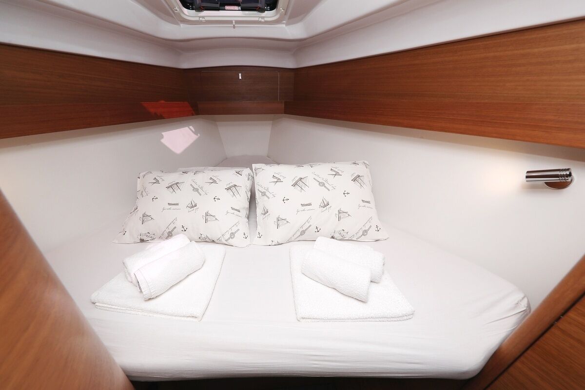 Une cabine compacte et bien éclairée, avec un lit agrémenté d’oreillers à motifs et de serviettes soigneusement pliées.