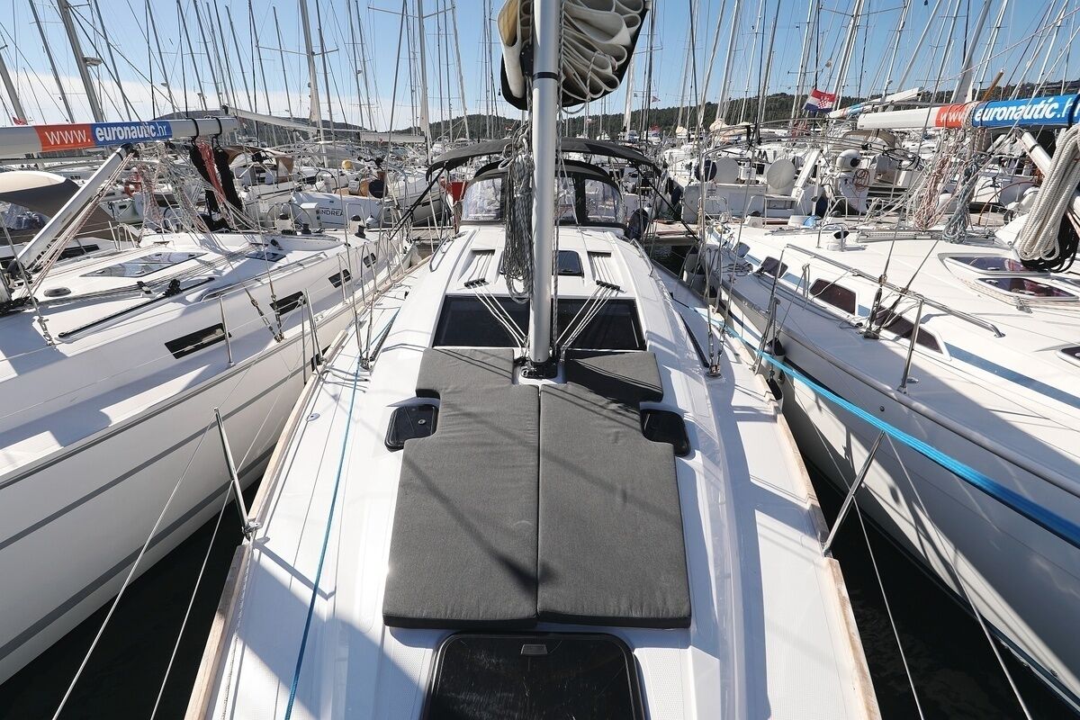 Una marina con diverse barche a vela ormeggiate, caratterizzata da una passerella centrale e sartiame sospeso.