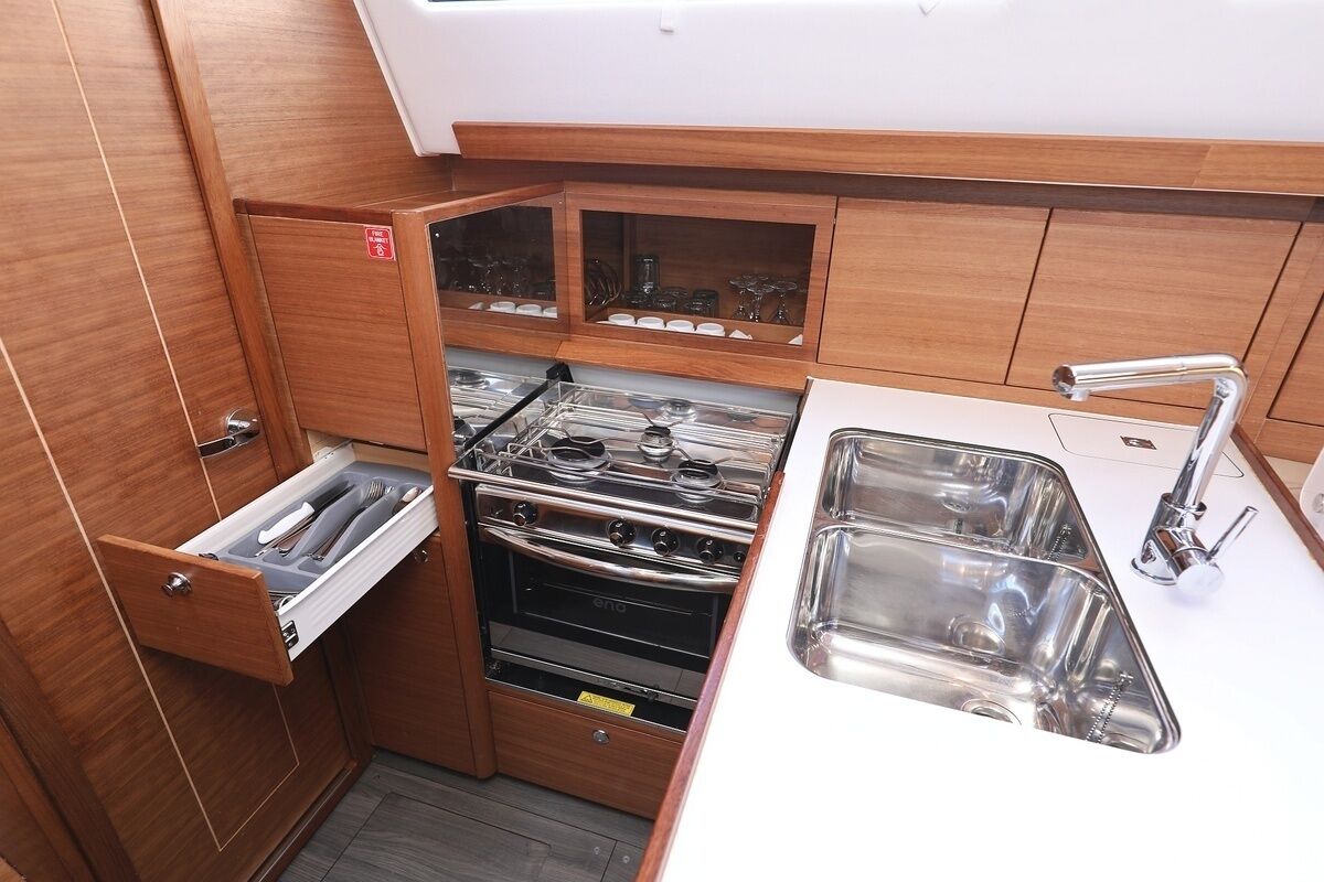 A compact kitchen with a built-in oven, a sink, and a drawer unit.