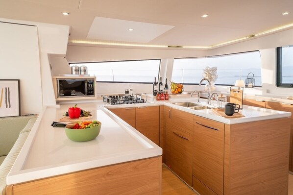 A modern kitchen with a microwave, sink, and wooden cabinets. - Caribbean Sun-Kissed Sailing: A Luxurious Beach Experience from Martinica, Le Marin (Le Marin)