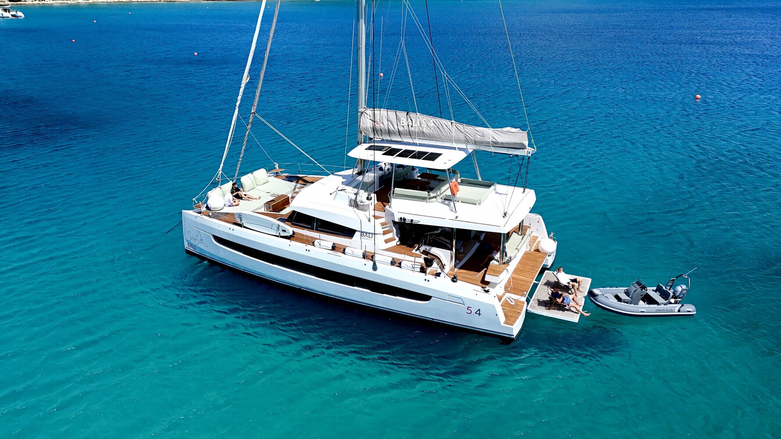 Un grand yacht doté d’un pont spacieux, d’un espace salon abrité et d ’un petit bateau amarré à proximité.
