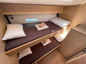 A bunk bed with a window, wooden headboard, and a small cabinet.