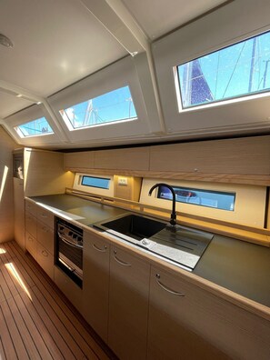 Une cuisine compacte dotée de fenêtres de toit, d’un évier et de meubles de rangement en bois.