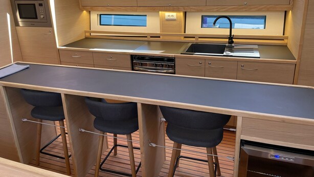 A compact kitchen with a microwave, stove, sink, and bar stools. - Sun-Kissed Sailing Adventure in Northern Croatia (Punat)