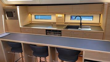 Une cuisine compacte équipée d’un four à micro-ondes, d’une cuisinière, d’un évier et de tabourets de bar.