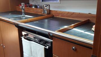 Une petite cuisine équipée avec une cuisinière, un évier et des placards en bois.
