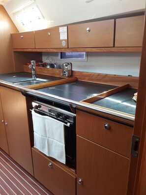 Una kitchenette compacta con estufa, pileta y armarios de madera.