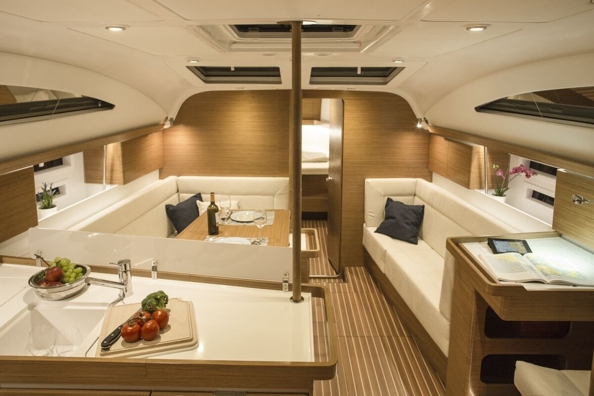 A modern interior with a central seating area, a dining table, and a small kitchen area.