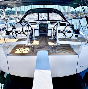 Das Deck eines Bootes mit Steuer, Bedienfeld und Sitzgelegenheiten.