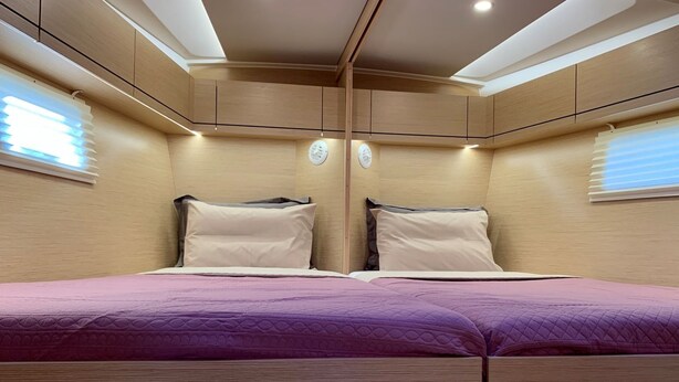 Quarto com uma cama, duas mesas de cabeceira, uma janela com persianas e iluminação embutida no teto.