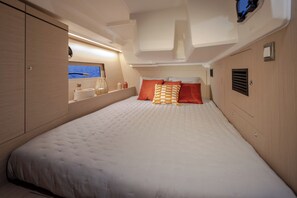 Ein Schlafzimmer mit Bett, Kissen, einem Nachttisch, einem Spiegel und einem Fenster mit Blick.