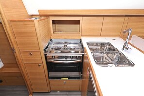 A compact kitchen with a stove, oven, and sink. - Sun-Kissed Sailing Adventure in Zadar, Croatia (Biograd na moru)