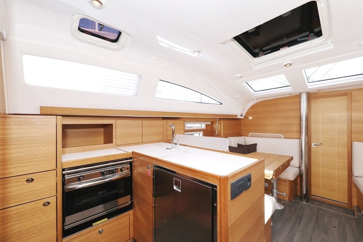 Una cocina pequeña y funcional con estufa, refrigerador y pileta, muebles de madera y tragaluz.