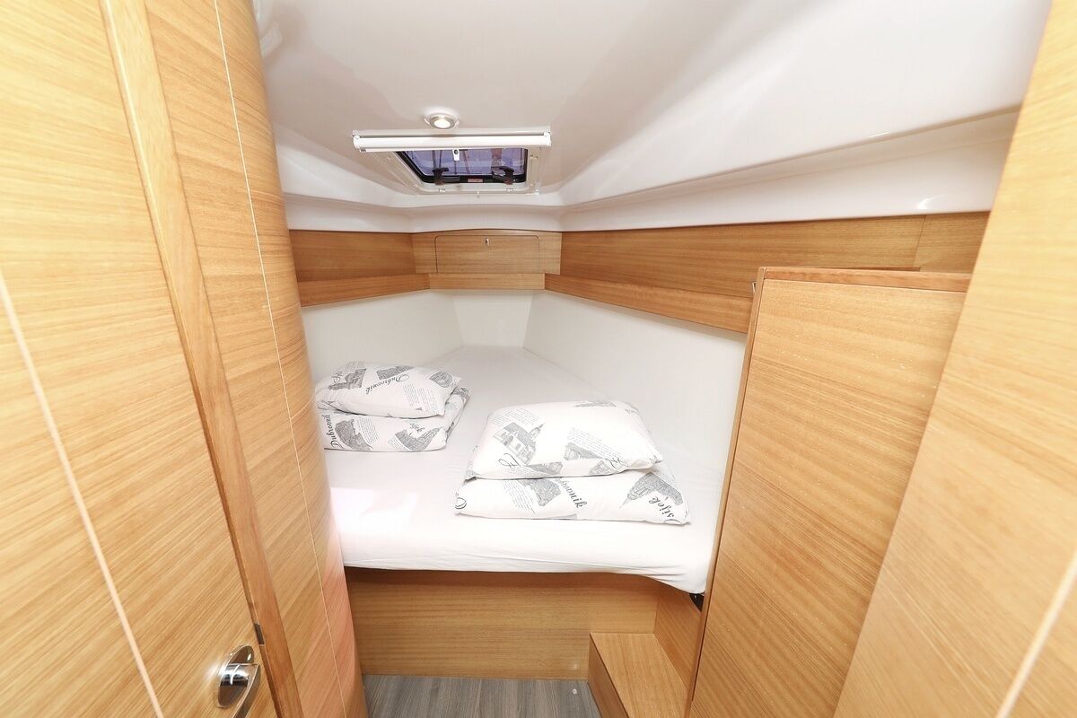 Una cabaña pequeña con literas, un tragaluz y paneles de madera.