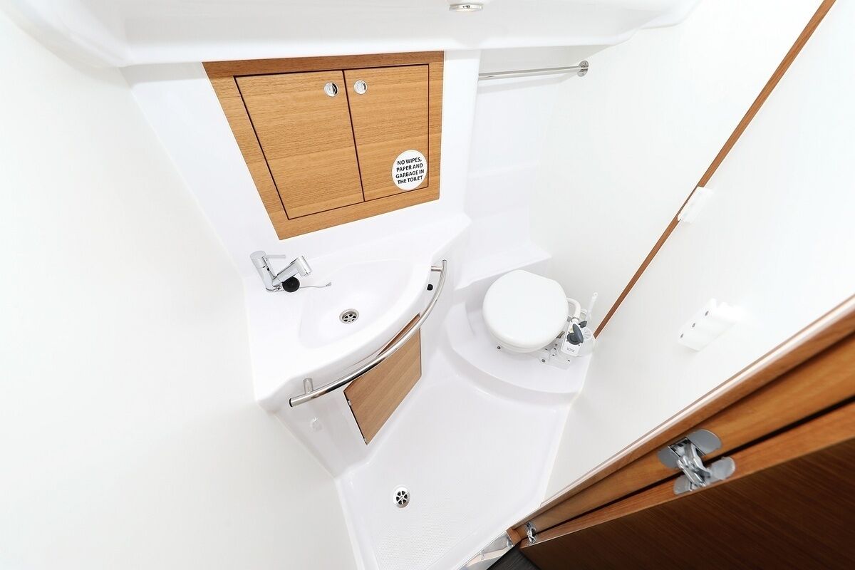 A compact bathroom with a wooden cabinet, a toilet, and a sink.