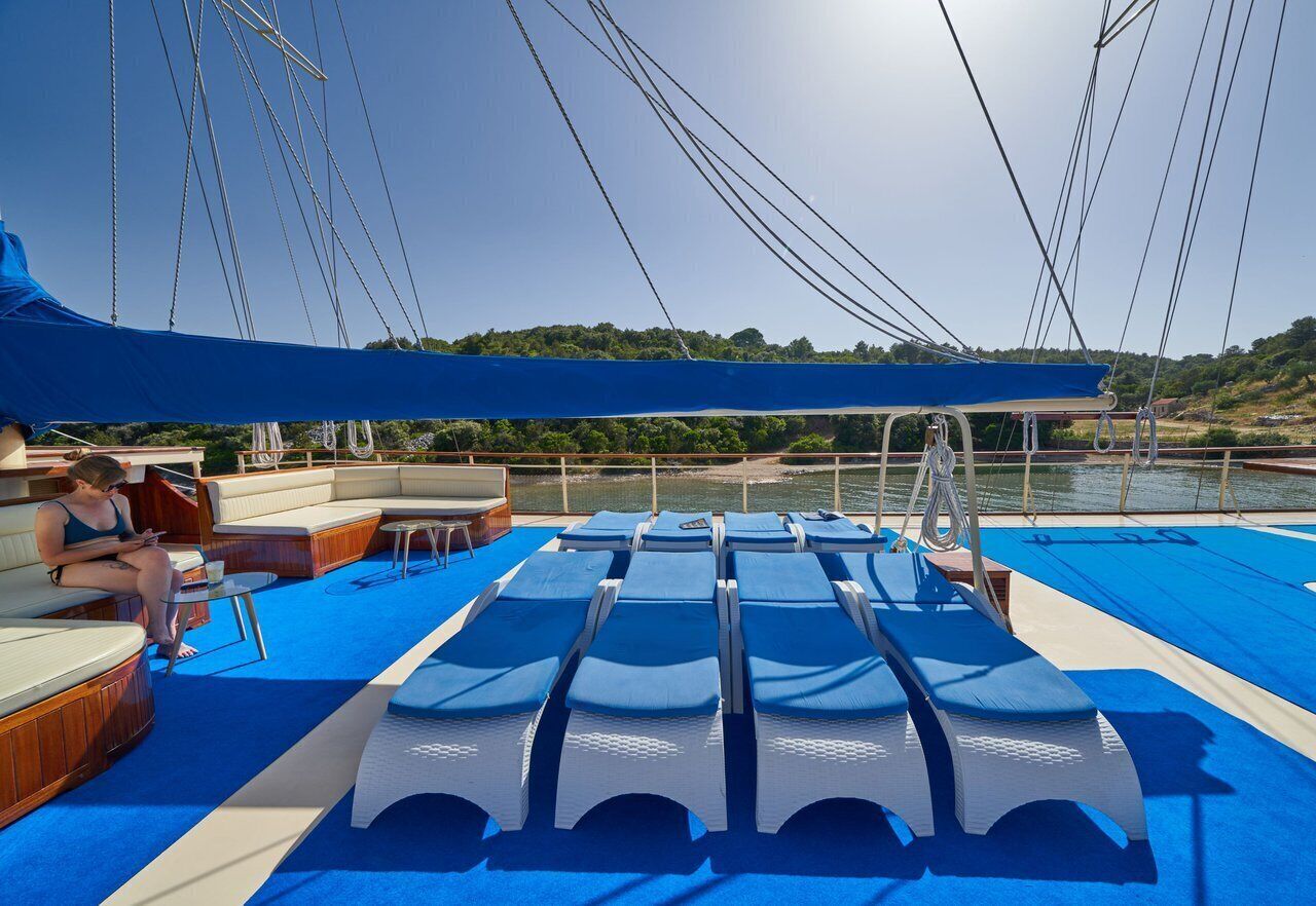 A sun deck with lounge chairs, a covered seating area, and a view of the water.