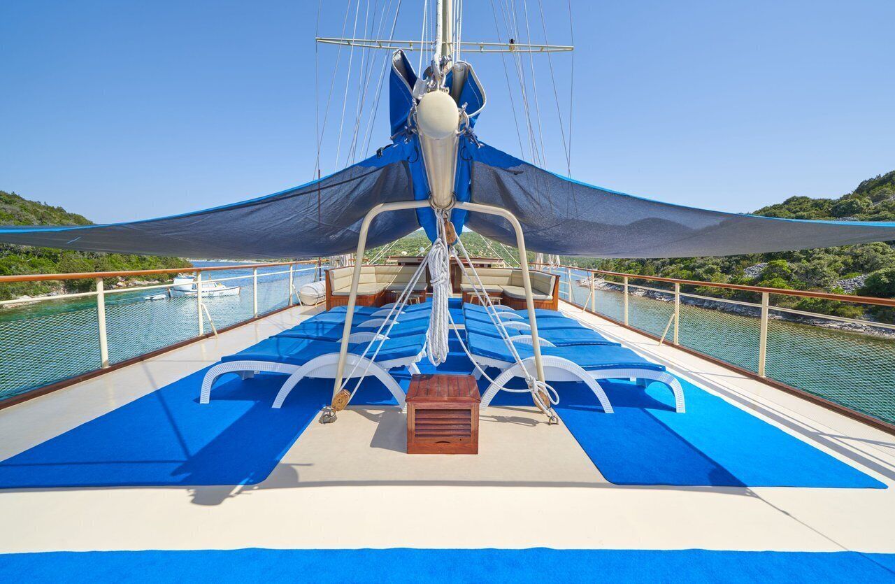 A sailboat deck with a mast, sails, and a small wooden chest.