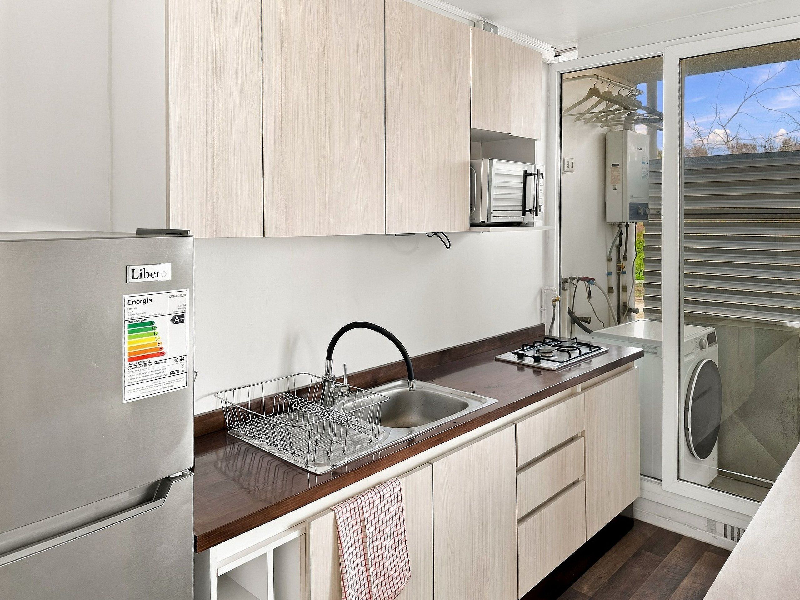 A compact kitchen with a built-in dishwasher, a gas stove, and a window with blinds.