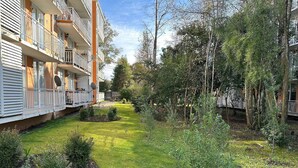 A courtyard with a grassy area, small shrubs, and trees. - Oceana Suites Pucón vista al volcán (Pucon)