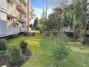 A courtyard with a grassy area, small shrubs, and trees. - Oceana Suites Pucón vista al volcán (Pucon)