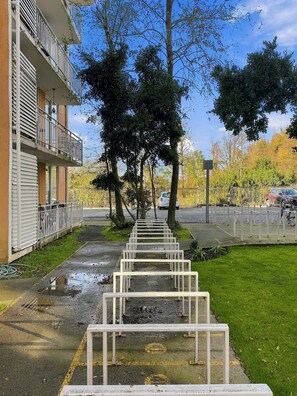 A pathway lined with white metal barriers, a building with a balcony, and trees in the background. - Oceana Suites Pucón vista al volcán (Pucon)