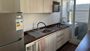A compact kitchen with a stainless steel refrigerator, a microwave, a sink, and a gas stove. - Oceana Suites Pucón vista al volcán (Pucon)