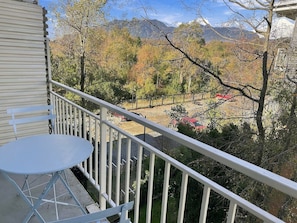 Varanda com mesa e cadeiras, com vista para uma paisagem montanhosa coberta por folhagem de outono.