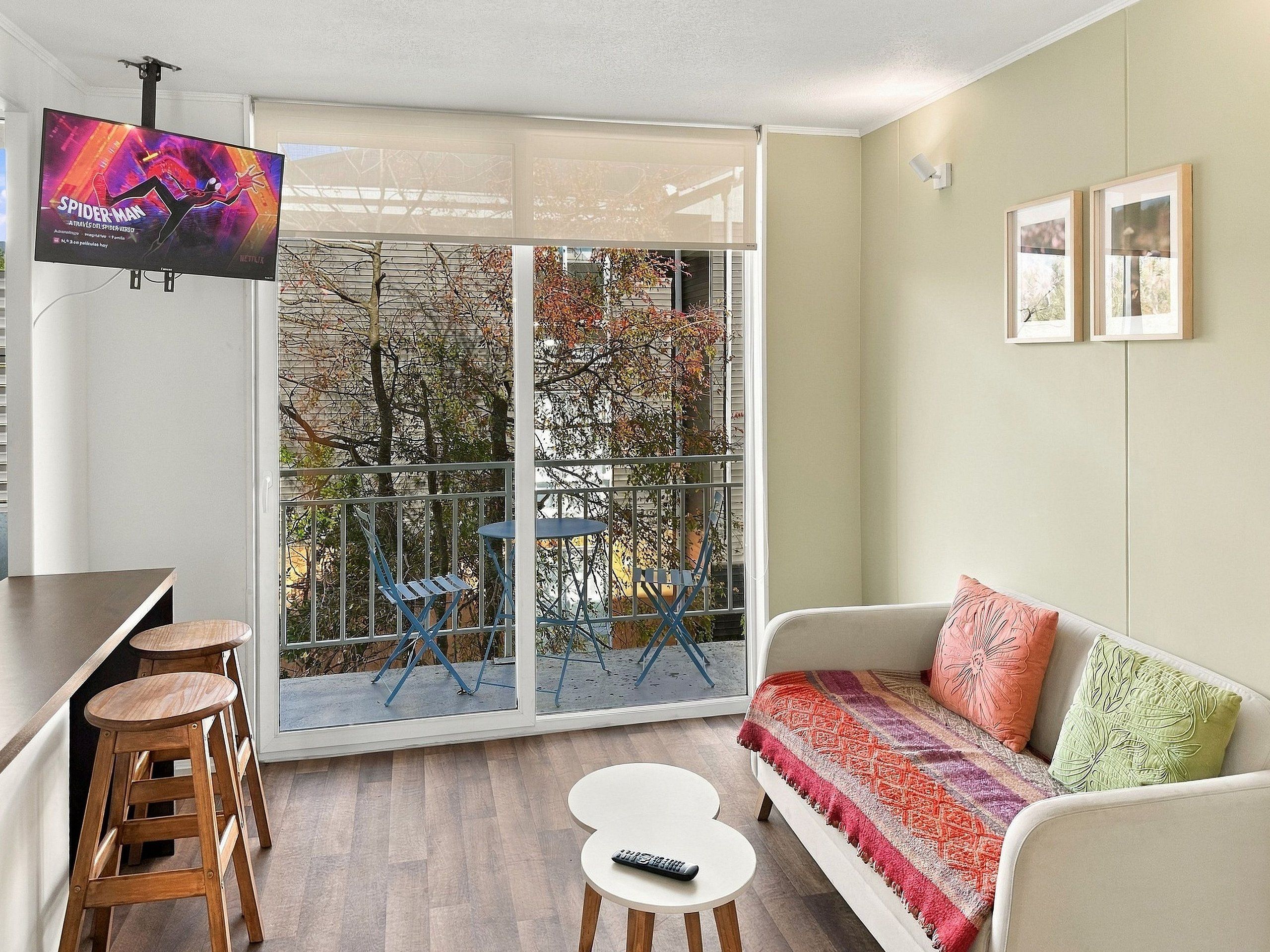 A living room with a sofa, a small round table, and a TV mounted on the wall.