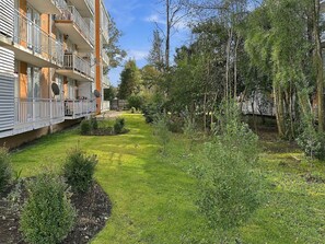Un edificio residencial con varios balcones, un césped cuidado y árboles circundantes.