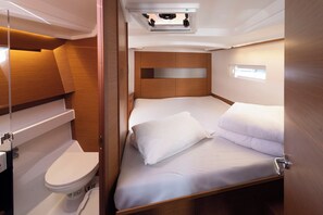 Una cabaña pequeña y luminosa con cama, inodoro y un ventanal.