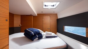 A modern bedroom with a bed, a window with a view of the sea, a skylight, and wooden paneling. - Sun-Kissed Sailing Adventure in Sibenik, Croatia (Primošten)